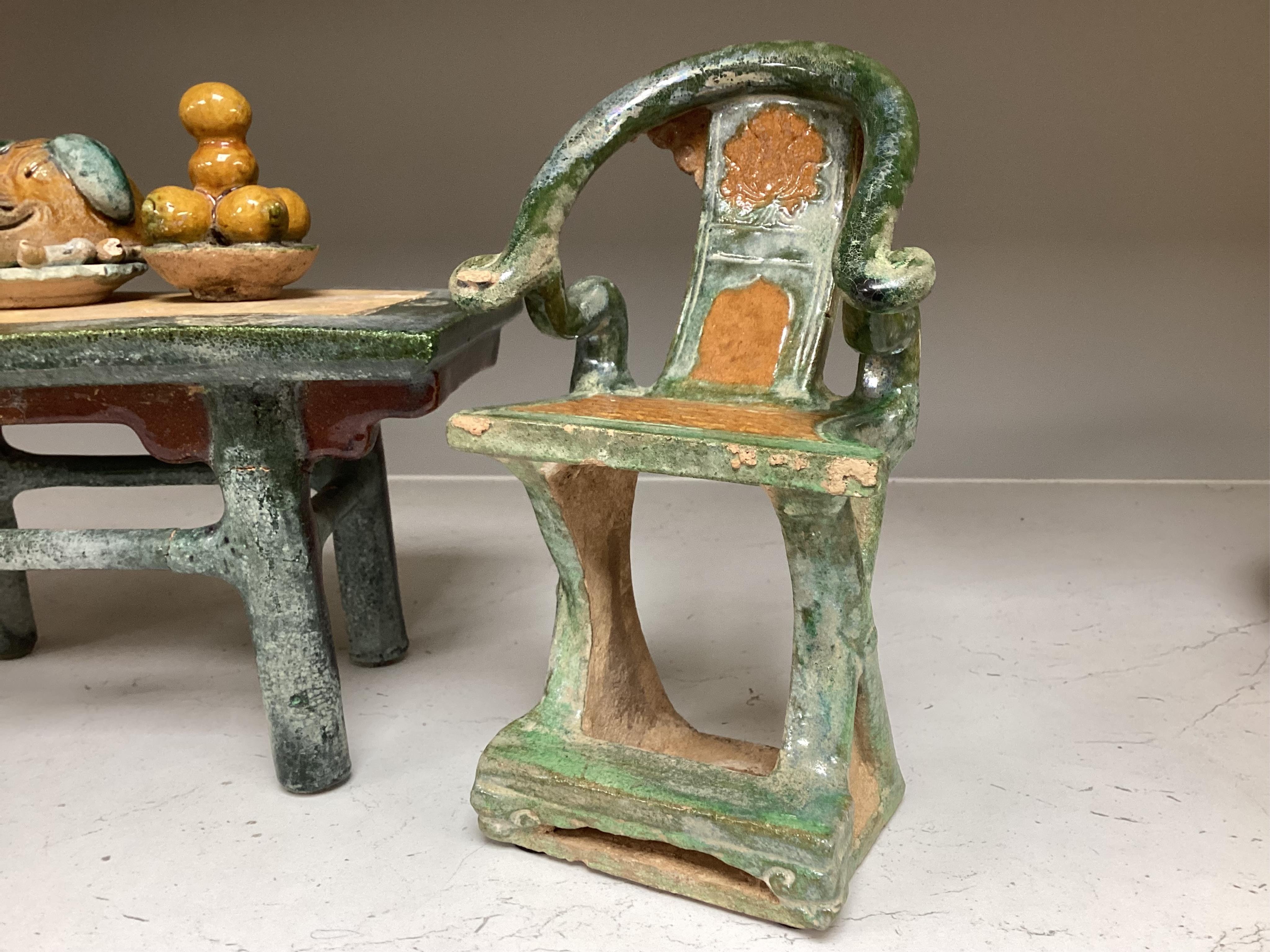 A set of Chinese Ming Sancai models of table with offerings and a pair of horseshoe shaped armchairs, 16th century, the chairs each 22cm high